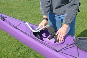 A man storing a WheelEEZ mini kayak cart in the kayak storage bin