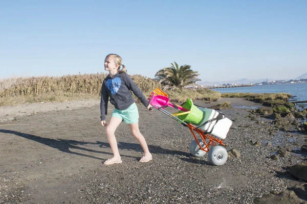 A girl pulling a WheelEEZ Mini Beach Cart loaded with gear